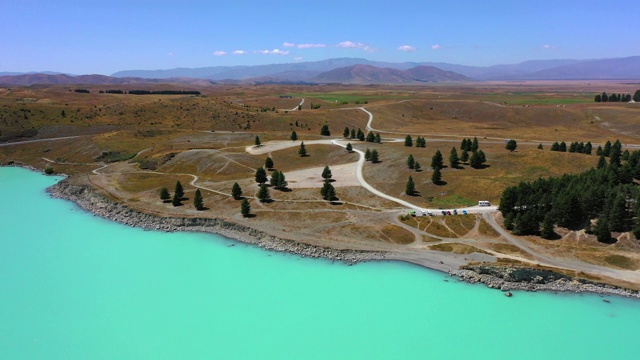 空中平移拍摄的道路附近的绿松石湖对天空在晴朗的一天，无人机飞过附近山脉的景观-普卡基湖，新西兰视频素材