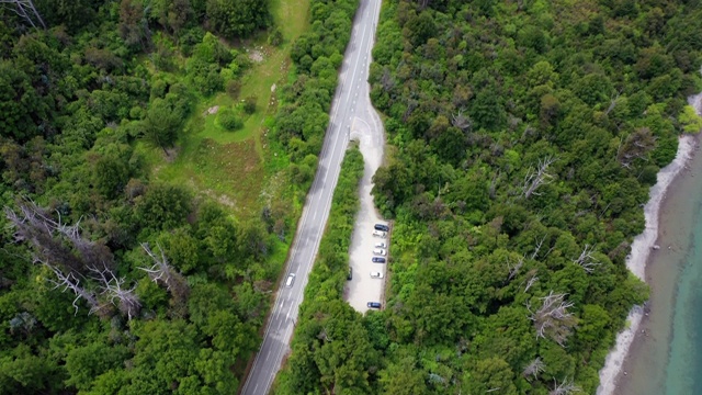 航拍的道路上的汽车在绿树中接近城镇的湖边，无人机飞过森林-皇后镇，新西兰视频素材