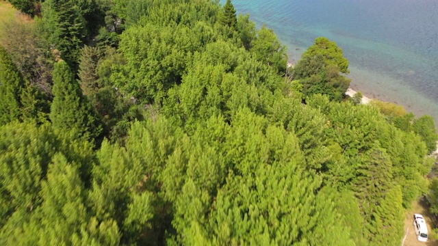 空中倾斜拍摄的车辆在湖岸的树木，无人机飞向山脉的天空在晴朗的一天-皇后镇，新西兰视频素材