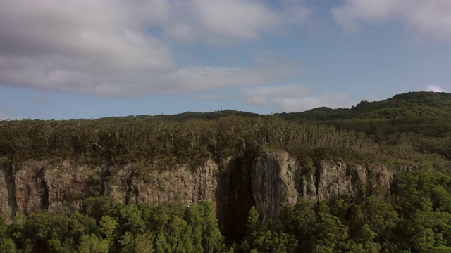 空中拍摄的森林岩石悬崖上的绿树对天空，无人机飞过斯普林布鲁克国家公园在晴朗的一天视频素材