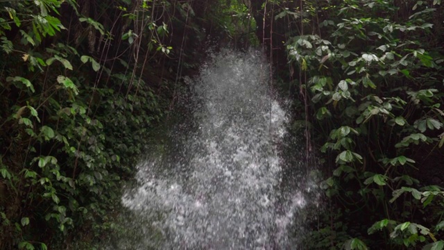 慢镜头倾斜下拍摄的瀑布溅在绿色植物在雨林-龙目岛，印度尼西亚视频素材