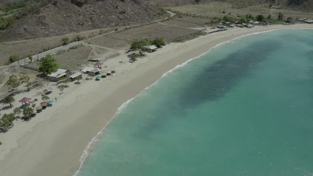 空中摇摄海浪溅在海滩上在阳光明媚的一天，无人机飞过绿松石海-龙目岛，印度尼西亚视频素材