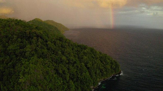 空中摇摄彩虹在海附近的绿色山脉对天空，无人机在日落时飞过风景-瓦卡托比摄政，印度尼西亚视频素材