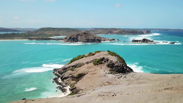 无人机拍摄的印度尼西亚龙目岛丹戎安海滩田园诗般的海岬。海湾周围是悬崖峭壁。水有许多深浅不一的蓝色。在海滩上放松的完美一天。视频素材