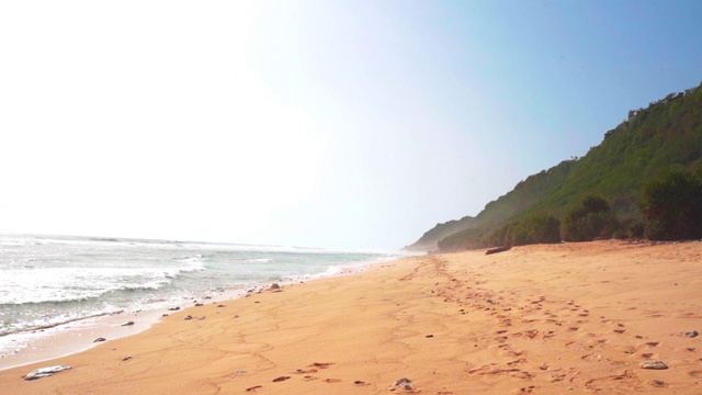 在阳光明媚的日子里，海浪在海滩上溅起浪花的镜头——巴厘岛沧谷视频素材