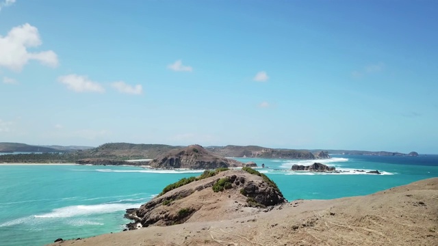 无人机拍摄的印度尼西亚龙目岛丹戎安海滩田园诗般的海岬。海湾周围是悬崖峭壁。水有许多深浅不一的蓝色。在海滩上放松的完美一天。视频素材