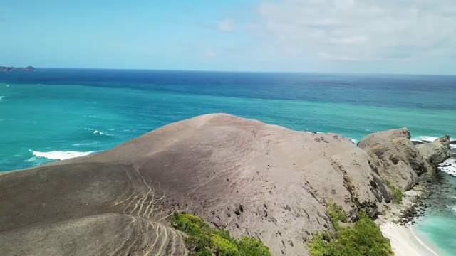 无人机拍摄的印度尼西亚龙目岛丹戎安海滩田园诗般的海岬。海湾周围是悬崖峭壁。水有许多深浅不一的蓝色。在海滩上放松的完美一天。视频素材