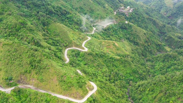 山路弯弯曲曲，沿着山坡山坡上覆盖着绿色的森林和植被。菲律宾吕宋岛视频素材