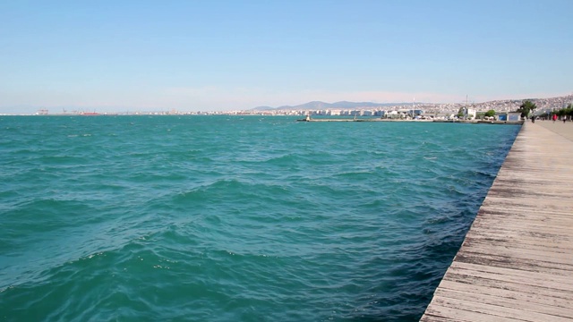 城市海岸，海浪很少的海洋和城市塞萨洛尼基的背景，希腊视频下载