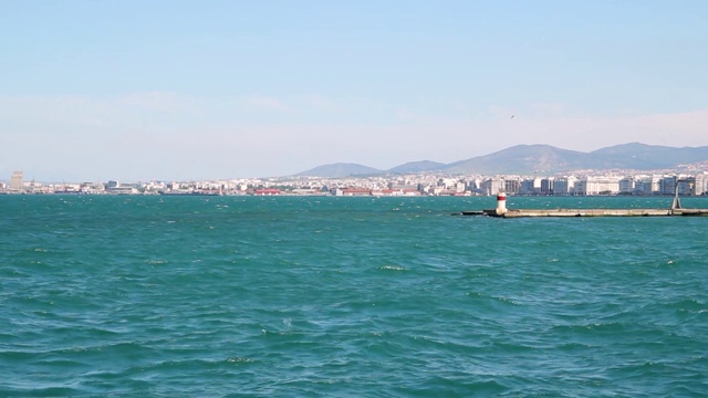 在海边的码头，蓝色的海水和城市塞萨洛尼基的背景，田园诗般的蓝天，希腊视频下载