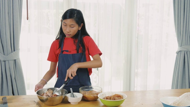 亚洲女孩在碗里用酱油腌制鸡肉，慢镜头视频素材