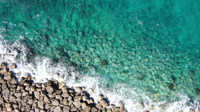 碧绿透明的水溅在海洋中的岩石上。鸟瞰泡沫晶莹剔透的海浪地中海塞浦路斯。海景优美，环境优美，是旅游胜地。视频素材