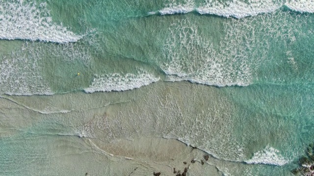 镜头跟随地中海的绿松石海浪。在塞浦路斯度假胜地的沙滩上翻滚的泡沫水俯视图。海景、自然、旅游、度假。视频素材