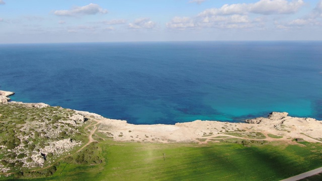 在地中海海岸线上的塞浦路斯绿色山谷的无人机视图。空中拍摄的荒芜的沙滩和平静的美丽的深蓝色的水在阳光。旅游、度假、自然、景观。视频素材