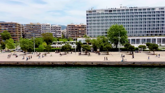 鸟瞰图城市海岸，公园与人，道路与汽车在希腊塞萨洛尼基，横向移动无人机。视频下载