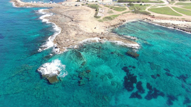 顶视图荒芜的海吐出透明的海水周围。蔚蓝清澈的地中海海浪与岩石在海底的鸟瞰图。晴朗的夏日，塞浦路斯的度假胜地。自然,美丽。视频素材