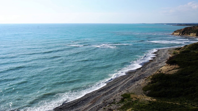 鸟瞰塞浦路斯海边。蔚蓝平静的地中海海浪在潮湿的卵石海滩上翻滚。海边傍晚的夕阳。自然，风景，鸟瞰，美景。视频素材