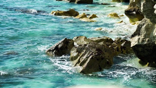 绿松石般的泡沫海浪在阳光下撞击岩石的特写。塞浦路斯地中海的岩石海岸。旅游胜地的晴天。海景、美、自然、环境。视频素材