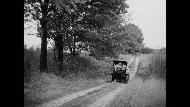 一对夫妇开着1910年的老爷车行驶在乡村公路上视频素材