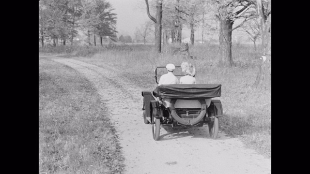 1910年一对夫妇在乡村公路上开着老爷车视频素材