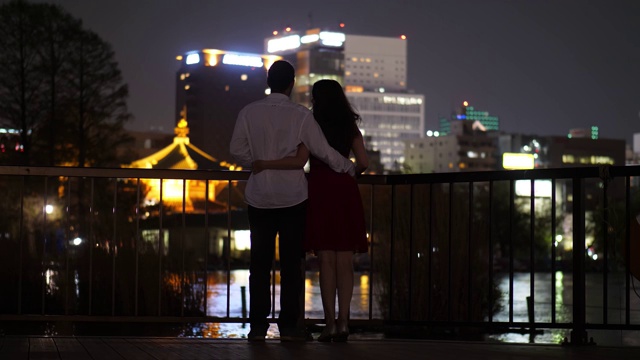 浪漫情侣在城市公园欣赏池塘，夜景拍摄视频素材