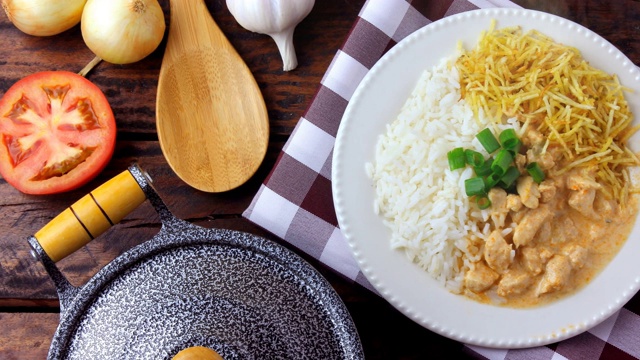 俄式炖鸡(Chicken stroganoff)源于俄罗斯美食，在巴西，这道菜由酸奶油、番茄汁、米饭和薯片组成，放在质朴的木桌上视频素材