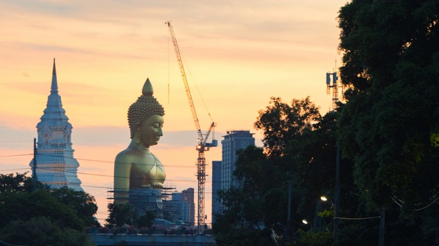 日落时分，泰国曼谷，正在修建的Wat Paknam Bhasicharoen寺的大金佛;缩小运动视频素材