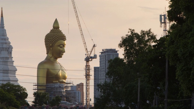 日落时分，泰国曼谷，正在修建的Wat Paknam Bhasicharoen寺的大金佛;缩小运动视频素材