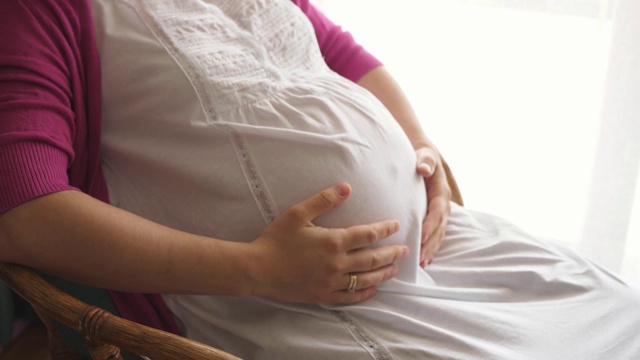 怀孕的女人感觉快乐期待母亲抱着婴儿在怀孕的肚子视频素材