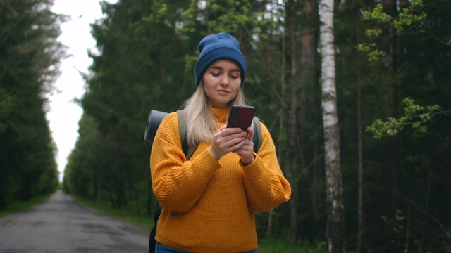 背包女孩使用智能手机Gps。在森林里徒步旅行的女人在智能手机上打字。独自使用智能手机的女性徒步旅行者。女性徒步旅行者用智能手机拍摄山脉和森林。视频素材