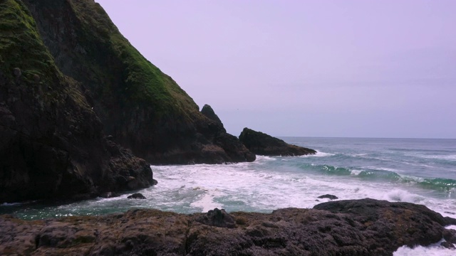 低低飞过海滩，掠过海浪拍打着岩石视频素材