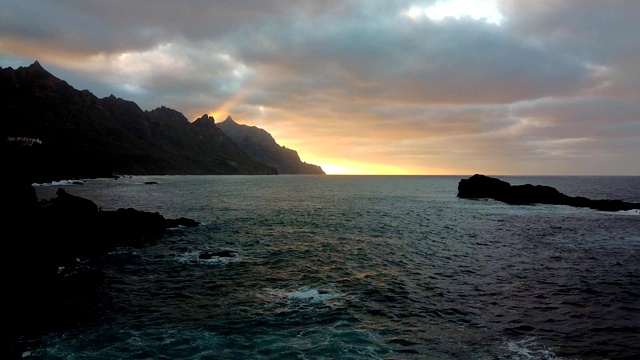 早晨日出黄昏。海浪，喧嚣的海洋。无人机航拍画面，海浪拍打着岩石。太阳从地平线升起，在山的后面视频素材