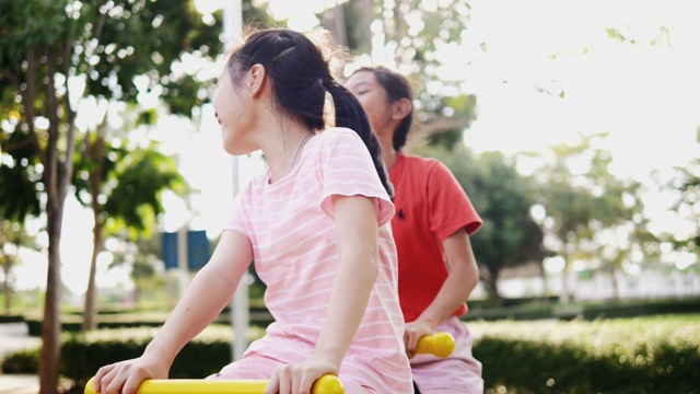 快乐的亚洲女孩一起在操场玩跷跷板。视频素材