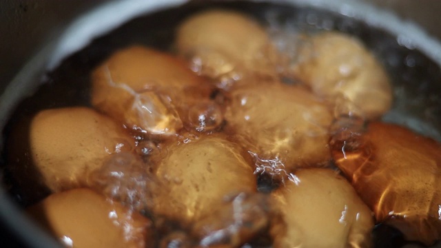 特写:在热水中煮鸡蛋，慢镜头。视频素材