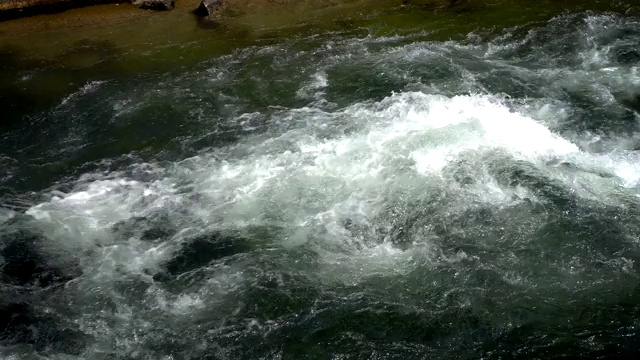 河水湍急，撞在岩石上视频素材