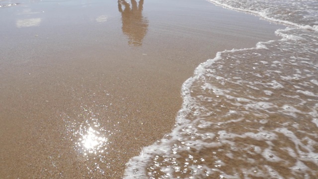 放松清澈的海水，在细沙沙滩上铺展着浪花视频素材