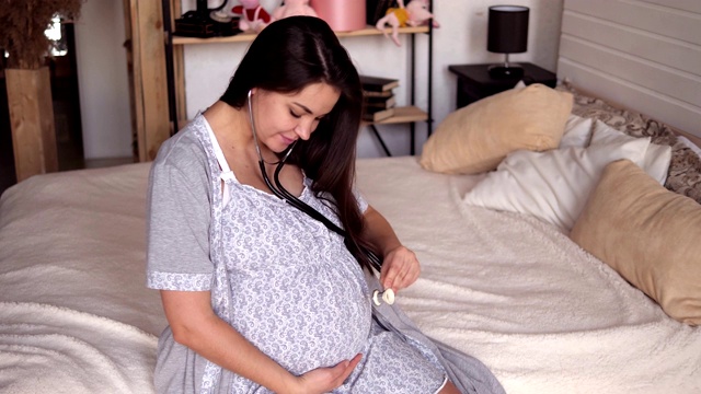 特写孕妇与听诊器在腹部听婴儿。视频素材