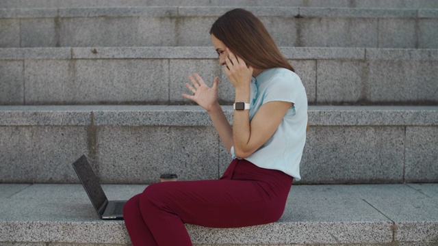 商业女性在笔记本电脑上阅读好消息。女员工用智能手机聊天视频素材