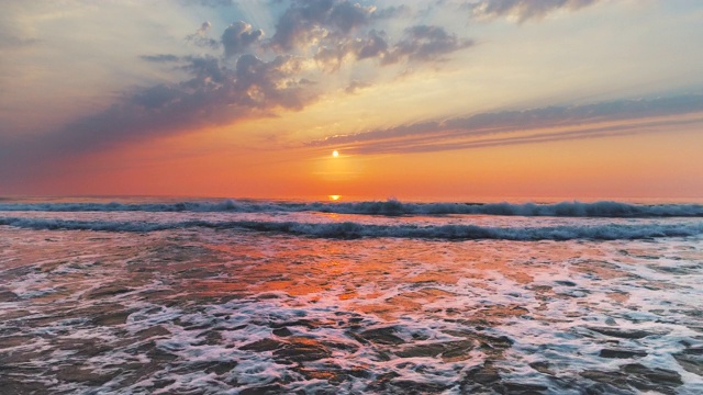 大海日出，浪花溅在沙滩上视频素材