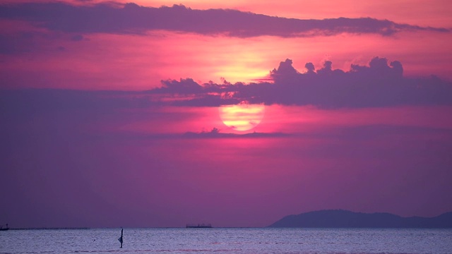 夕阳和紫云在天空，海面上小波浪移动渔船视频素材