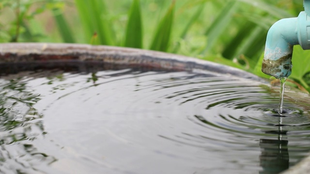 特写:水面满是旧塑料水龙头流出的水滴。视频素材