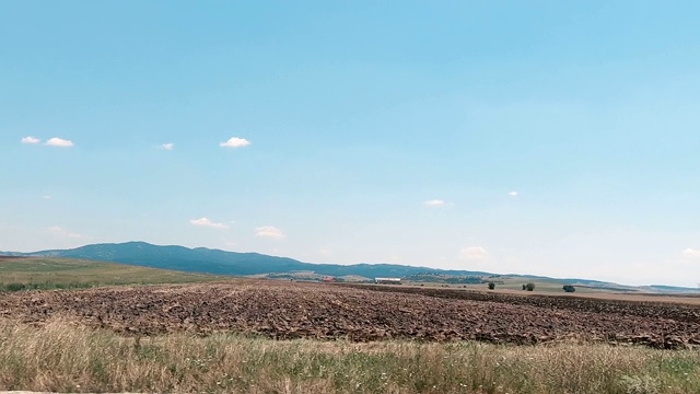 在一个晴朗的夏日，沿着田野和草地缓慢地行驶视频素材