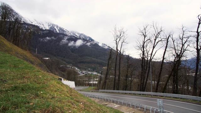 令人惊叹的风景，一条山路和一辆行驶的汽车在云雾背景与雪山。资料片。山路蜿蜒，车辆行驶视频素材