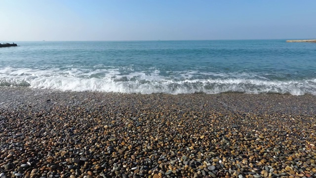 平静的大海。卵石滩上的弱浪。海边的晴天视频素材