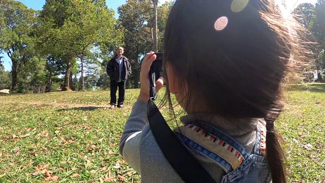 亚洲女孩带着相机在自然领域。一位年轻的女摄影师在公园里为一棵树拍照。技术和教育的概念，了解自然。视频素材