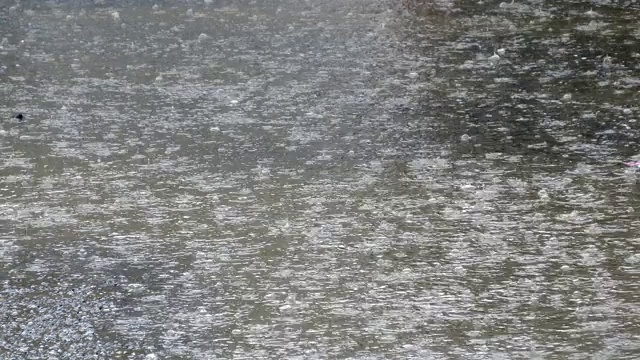 雨水落在被水淹没的街道水坑上，背景循环视频素材