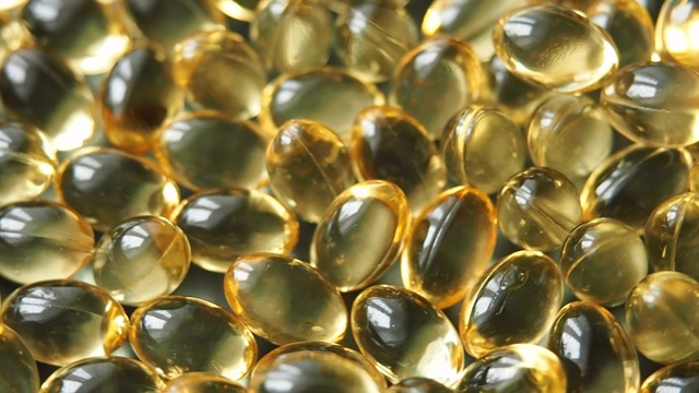 明亮的金黄色的omega-3维生素或鱼油胶囊旋转。关闭了。视频素材