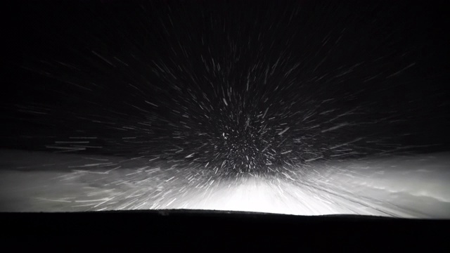 一辆汽车在暴风雪中行驶在夜晚的雪道上视频素材