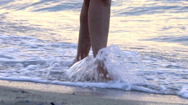 在夏天的海滩上，年轻女子沿着海浪的海水和沙子走着。旅行的概念。视频素材