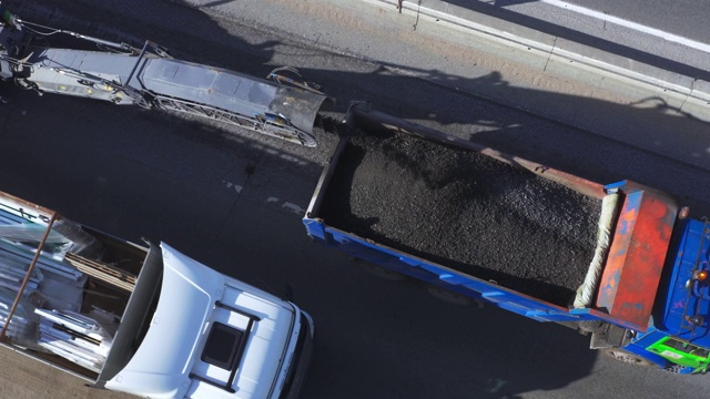 沥青碾磨将沥青表面从道路上磨碎，然后装入卡车，鸟瞰图视频素材